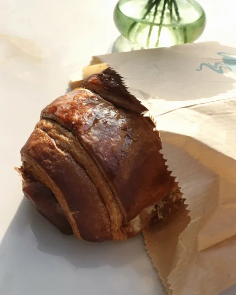 Croissant in einer Bäckertüte aus Papier mit gezacktem Rand